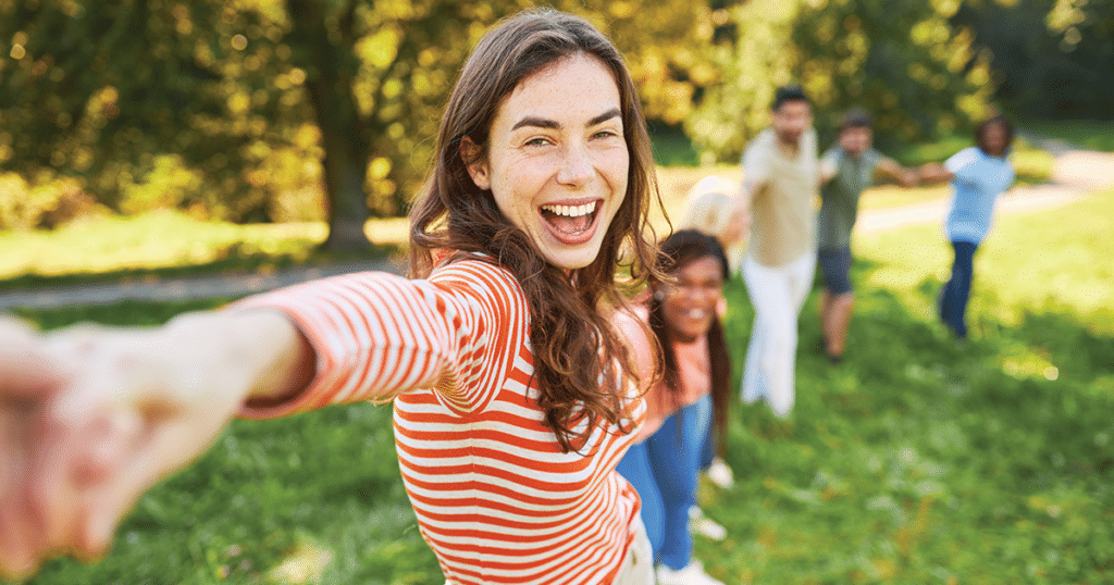 Group of teens joining hands outdoors.