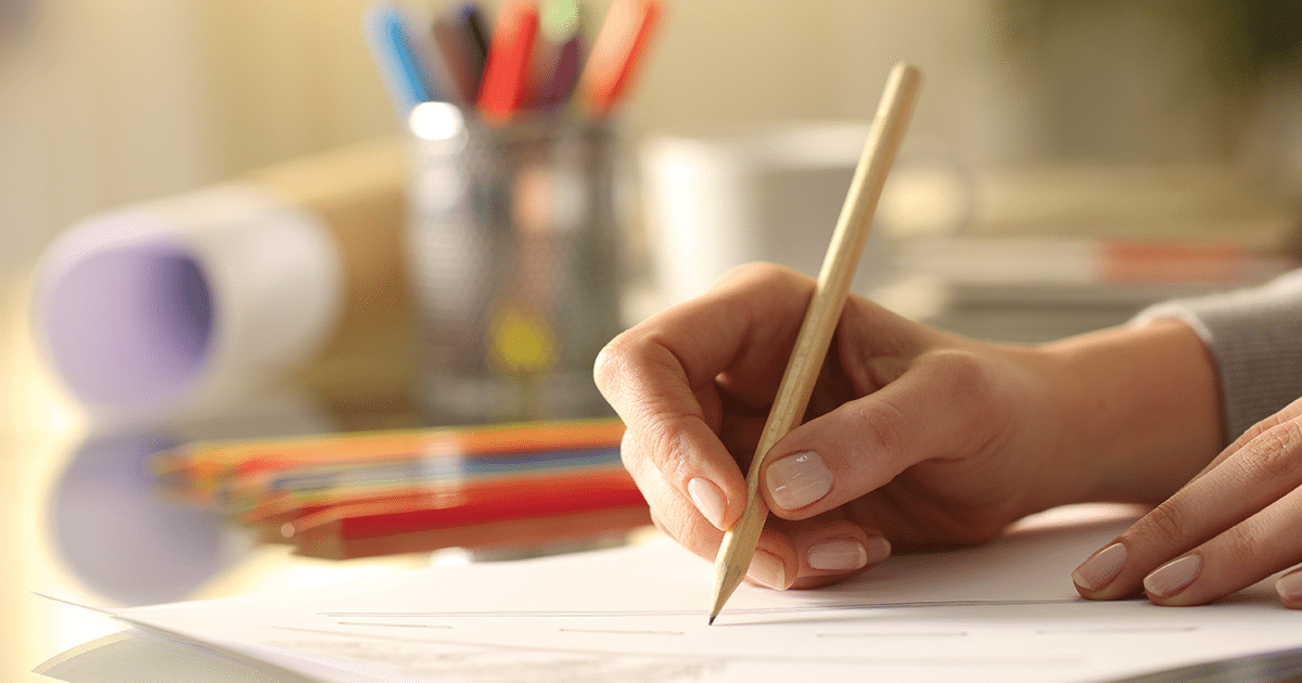 Hand with a pencil writing on paper.